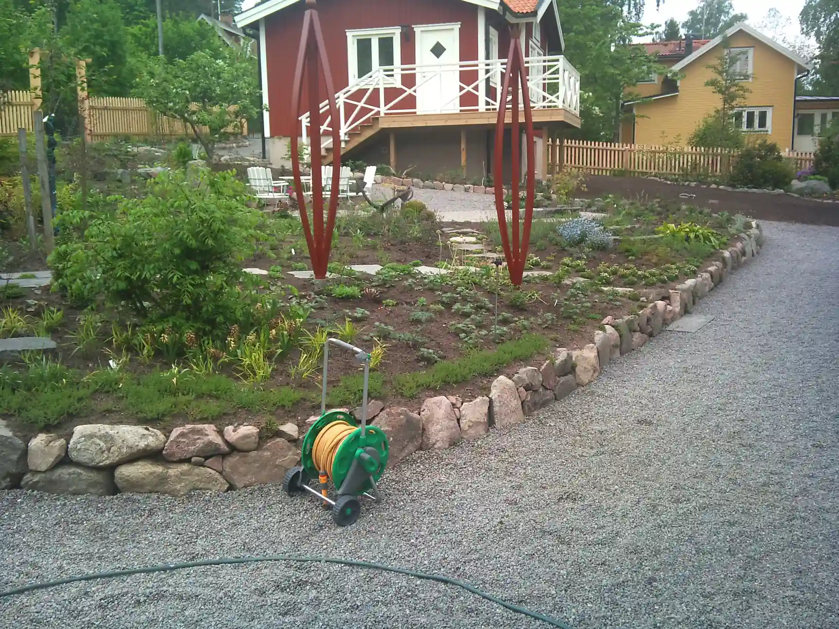Grusgång, stenmur och plantering med skulpturer